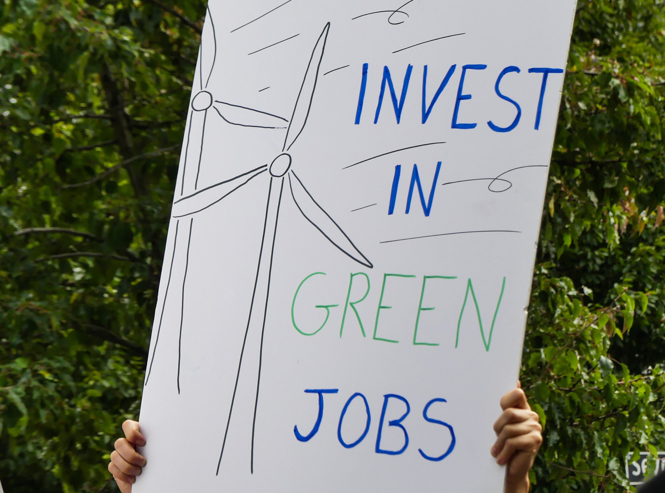 A person holding a sign that reads "Invest in Green Jobs"